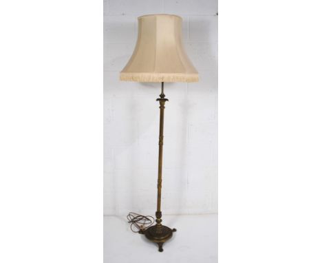 An antique brass standard lamp, with reeded decoration, on tripod claw feet