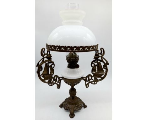 A Vintage brass oil lamp with white ceramic reservoir, and art nouveau brass decoration with sailing boat, glass chimney and 