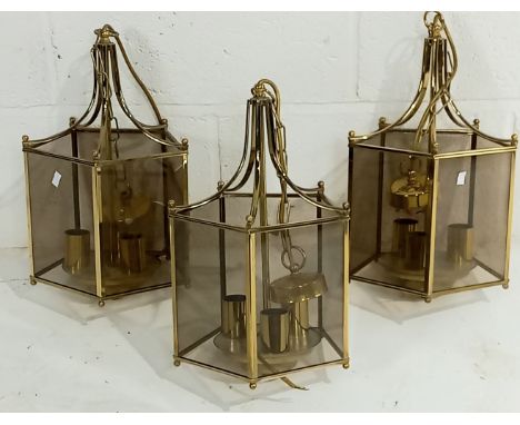 A set of three smoked glass and brass lantern style pendant light fittings.