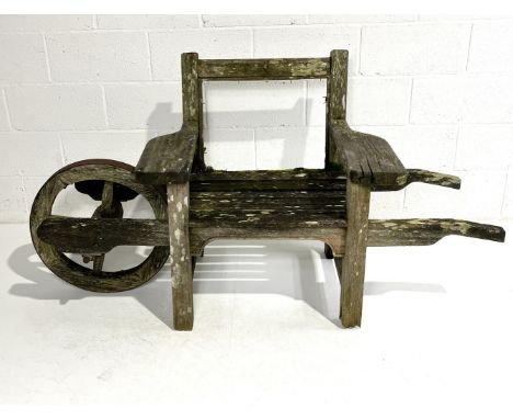 An Andrew Crace weathered teak wheelbarrow single seat garden bench A/F