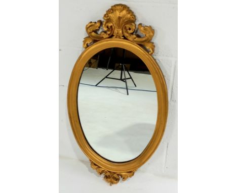 A vintage oval gilt framed wall mirror, 93cm high, 50cm wide.