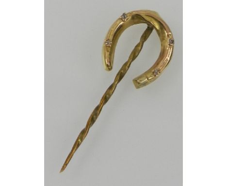 A yellow metal and diamond set tie pin in the form of a horseshoe. 