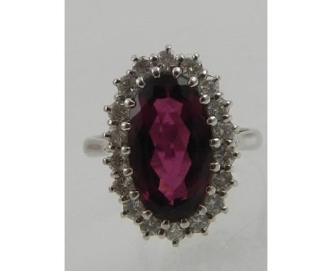 An 18 carat white gold, diamond, and amethyst cocktail ring, set central oval cut amethyst surrounded by small diamonds. 