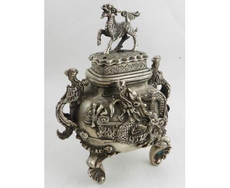 A Chinese white metal twin handled incense burner, moulded with dragons, raised on tripod feet, bears four character marks to