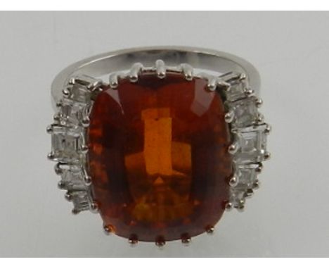An 18 carat white gold, diamond, and citrine cocktail ring, set central faceted orange citrine, flanked by two rows of five g