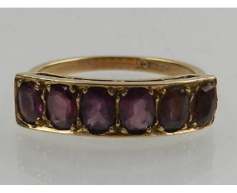 A 9 carat yellow gold and six stone amethyst ring, the oval cut amethysts framed in a rectangular mount. 