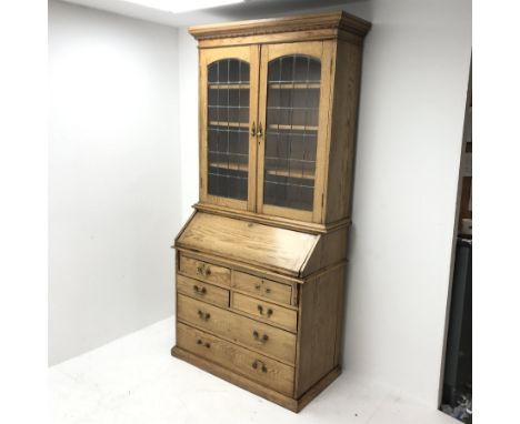 Early 20th Century light oak bureau bookcase, two lead glazed doors, three adjustable shelves above fall front enclosing fitt