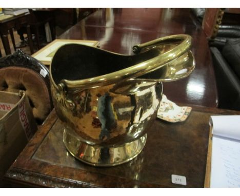 A BRASS COAL HELMET with swing handle raised on a circular spreading foot
