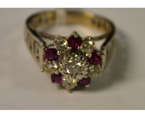 A ruby and diamond cluster ring, central raised round brilliant cut diamond, surrounded by a band of five vibrant red rubies 