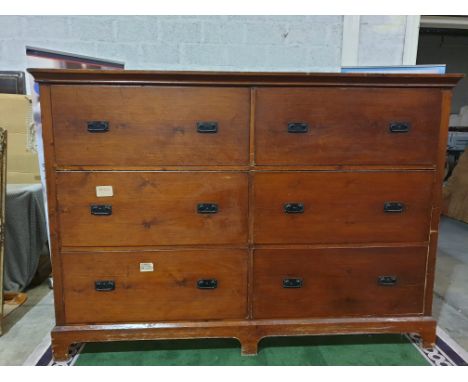 A large late Victorian stained pine chest of drawers. With two banks of three deep drawers, each with cast metal handles, on 