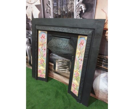 A Victorian Style cast iron black fire surround decorated with pink and yellow pot ceramic tiles with a scroll siamond motif 