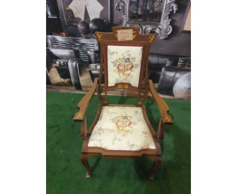 A mahogany and marquetry armchair.The flower and leaf-inlaid shaped toprail above an oblong padded back within open looped up