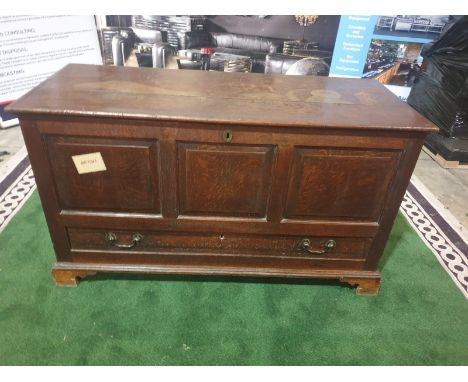 A George III oak `mule` chest. The planked hinged lid above a triple panel front and lower crossbanded drawer, on bracket fee