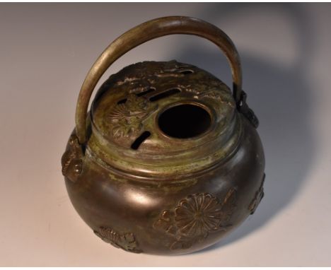 An Oriental dark patinated bronze hand warmer or brazier, cast and applied with flowering sprigs, swing handle, 21cm wide