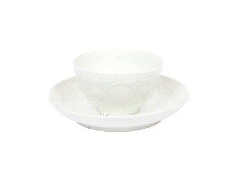 A VERY RARE LOWESTOFT TEA BOWL AND SAUCER. circa 1764, Of Hughes type and left in the white, moulded in relief with circular 