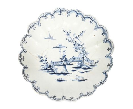 A LOWESTOFT PORCELAIN FLUTED JUNKET DISH, CIRCA 1765. the central field decorated in underglaze blue with a tall figure holdi