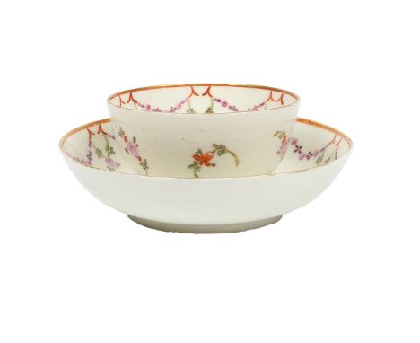 A RARE LOWESTOFT PORCELAIN TEA BOWL AND SAUCER. Inscribed in gilt "ANN GOUGE" to the tea bowl and saucer, with polychrome fol