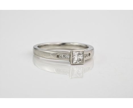 A platinum and diamond ring, The central princess cut stone flanked by diamond shoulders. Approximately 0.40ct total, ring si