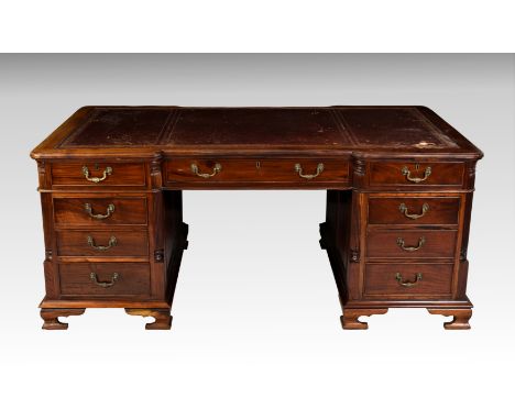 A 19th century style mahogany inverted breakfront partner's desk, 20th century, the top with inset red gilt tooled leather (a