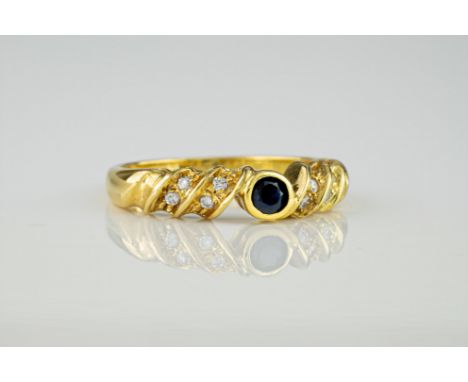 An 18ct yellow gold, diamond and sapphire ring, featuring a central, bevel set round cut sapphire of approximately 0.10ct and