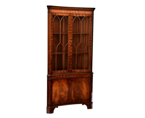 A Georgian style inverted bowfront corner cupboard, the dentil carved cornice over a pair of lancet astragal glazed doors enc