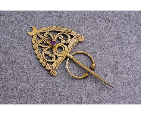 An Indian gold scarf pin with central ruby, the ruby of mixed, oval cut and pinkish red colour and measuring approximately 0.