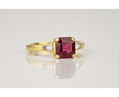 An 18ct yellow gold, ruby and diamond ring, the central, square cut ruby of deep red colouring and flanked by baguette cut di