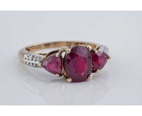 A ruby and diamond cocktail ring, featuring 3 rubies, the central oval cut ruby measuring approximately 9x6mm, flanked by 2 t