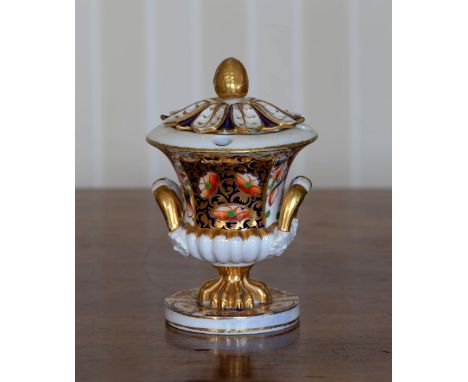 An early 19th century Derby urn form ink stand, with Imari style decoration, foliate cover with cone finial, twin gilt handle
