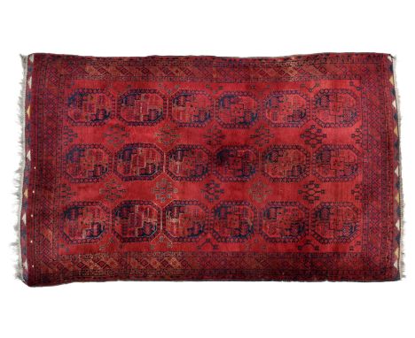 A large Afghan Bokhara rug, the three rows of six octagonal gols in dark blue, red and light brown, on a madder field, within