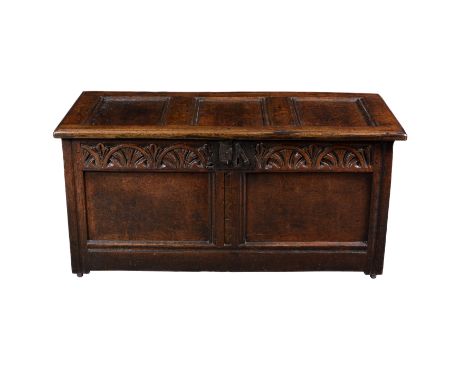 A small 18th century oak coffer, the three panel top on later hinges, over a two panel front with carved foliate arcaded frie
