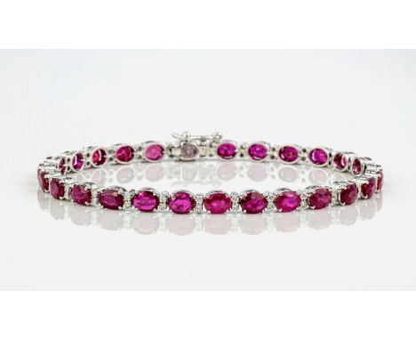 An 18ct white gold, ruby and diamond bracelet, featuring a row of deep red, oval cut rubies interspersed with round, brillian