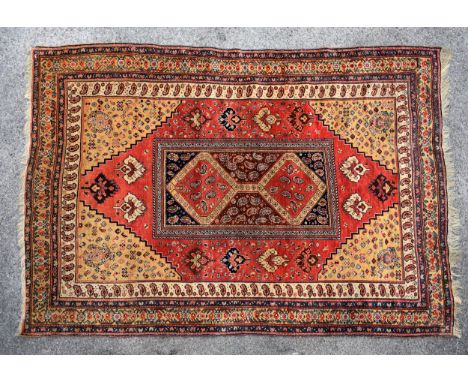 A Pakistani rug, 1st half 20th century, the central rectangular panel with two linked lozenge medallions with a repeating flo