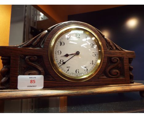 A carved oak mantle clock with enamelled dial Arabic numerals and French movement 