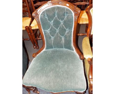 An Edwardian button-back nursing chair in blue upholstery resting on turned supports 