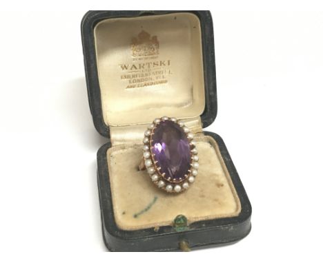 An unmarked rose gold vintage ring set with a large amethyst set in an oval of seed pearl ring size J in a fitted box total w