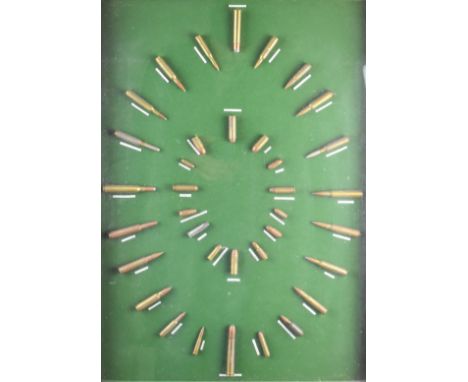 A rifle cartridge display board with thirty-six brass cartridges all labelled and mounted on green felt, framed and glazed, 8