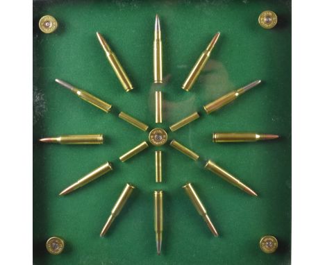 A rifle and shotgun cartridge display board with twenty-three brass cartridges and cartridge caps mounted on green felt, fram