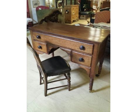 Old mahogany kneehole desk with a leather-topped chair. One long drawer over two short. Turned legs on brass-capped castors. 