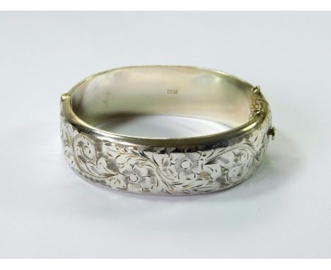 SILVER BANGLE. A Victorian-style, hinged silver bangle with engraved front. Birmingham 1962.  Please note that all items in t