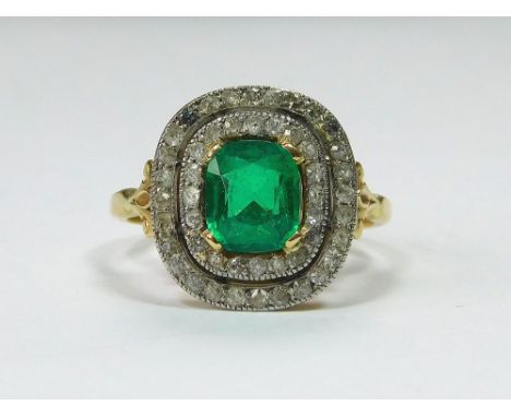 EMERALD RING. An Edwardian emerald & diamond cluster ring, set in yellow metal & platinum. The cushion-shaped emerald of appr