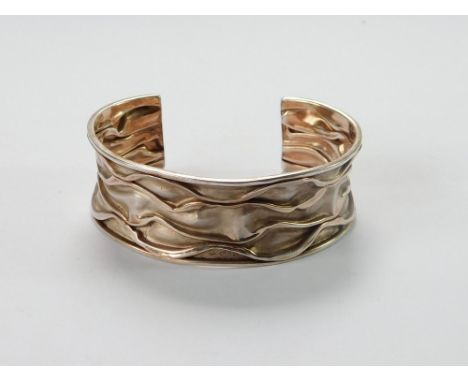 SILVER BANGLE. A contemporary silver (stamped 925) rose-tinted, hand made bangle. Depth 2.2cm. Opening 3.5cm.  Please note th