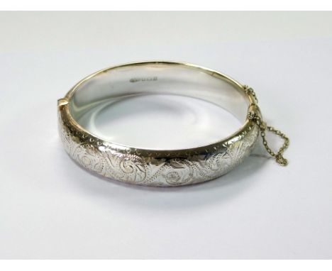 SILVER BANGLE. A modern silver, hinged bangle, with engraved front.  Please note that all items in this auction are previousl