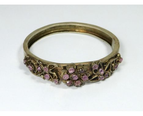 SILVER-GILT BANGLE. A vintage ruby & silver gilt hinged bangle, set with 19 stones. Possibly Sri Lankan.  Please note that al