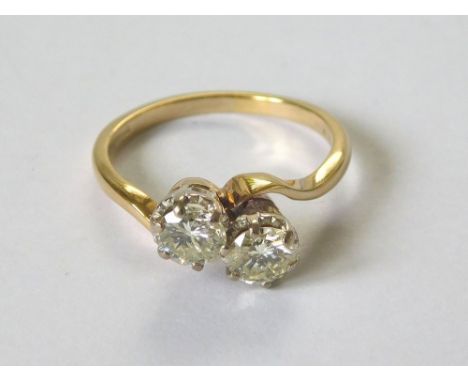 DIAMOND RING. An 18ct. gold, twin stone diamond cross-over ring. Each stone of approx. 0.80ct. spread. Size P.  Please note t