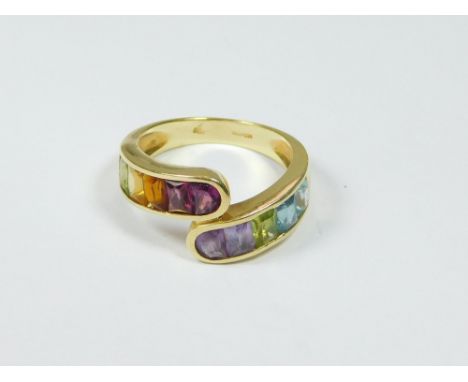 GOLD RING. An 18ct. gold, cross-over ring set a variety of semi-precious stones, comprising ten mostly rectangular stones, in