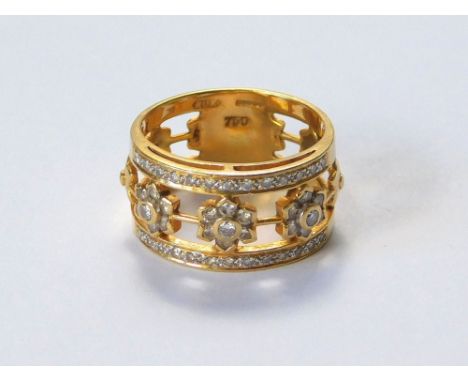 DIAMOND RING. An 18ct. gold diamond set ring, with an arrangement of three diamond flowerheads between two rows of diamonds. 