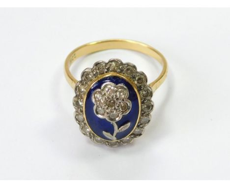 DIAMOND RING. An 18ct. gold diamond ring, at the centre a diamond flowerhead on a dark blue domed enamelled ground, surrounde