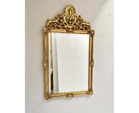 WALL MIRROR, 125cm high, 67cm wide, Baroque style, gilt frame, bevelled edge glass, shell moulded finial. 
