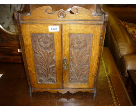 Early 20th Century carved oak smokers cabinet with two panel doors enclosing a fitted interior with accessories